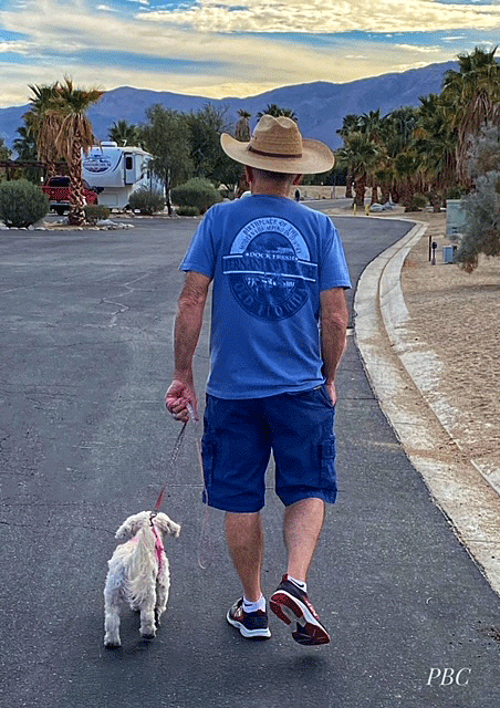 Man in cowboy hat walking with little white dog in Borrego Springs  RV park